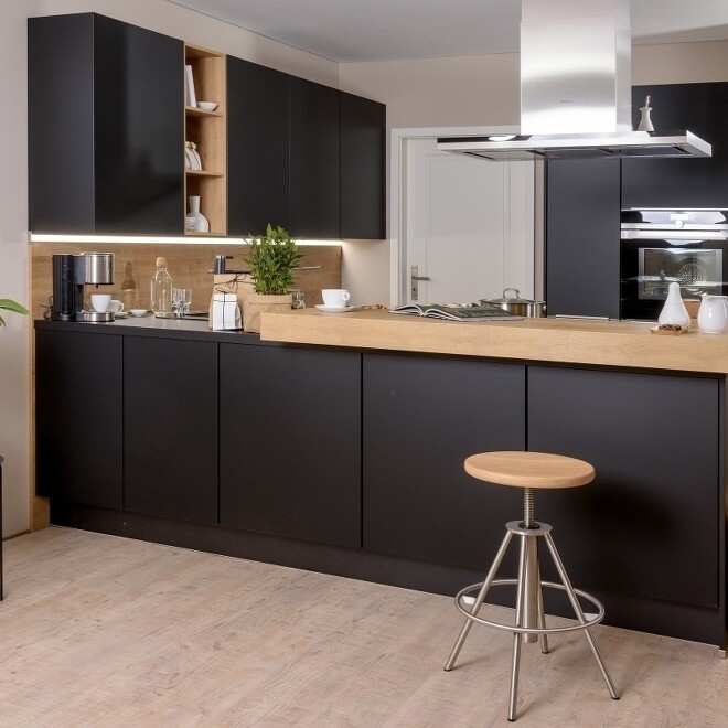 Schwarzes Küchendesign mit freistehender Küchentheke, die auch als Esstheke fungiert Schwarzes Küchendesign mit freistehender Küchentheke, die auch als Esstheke fungiert